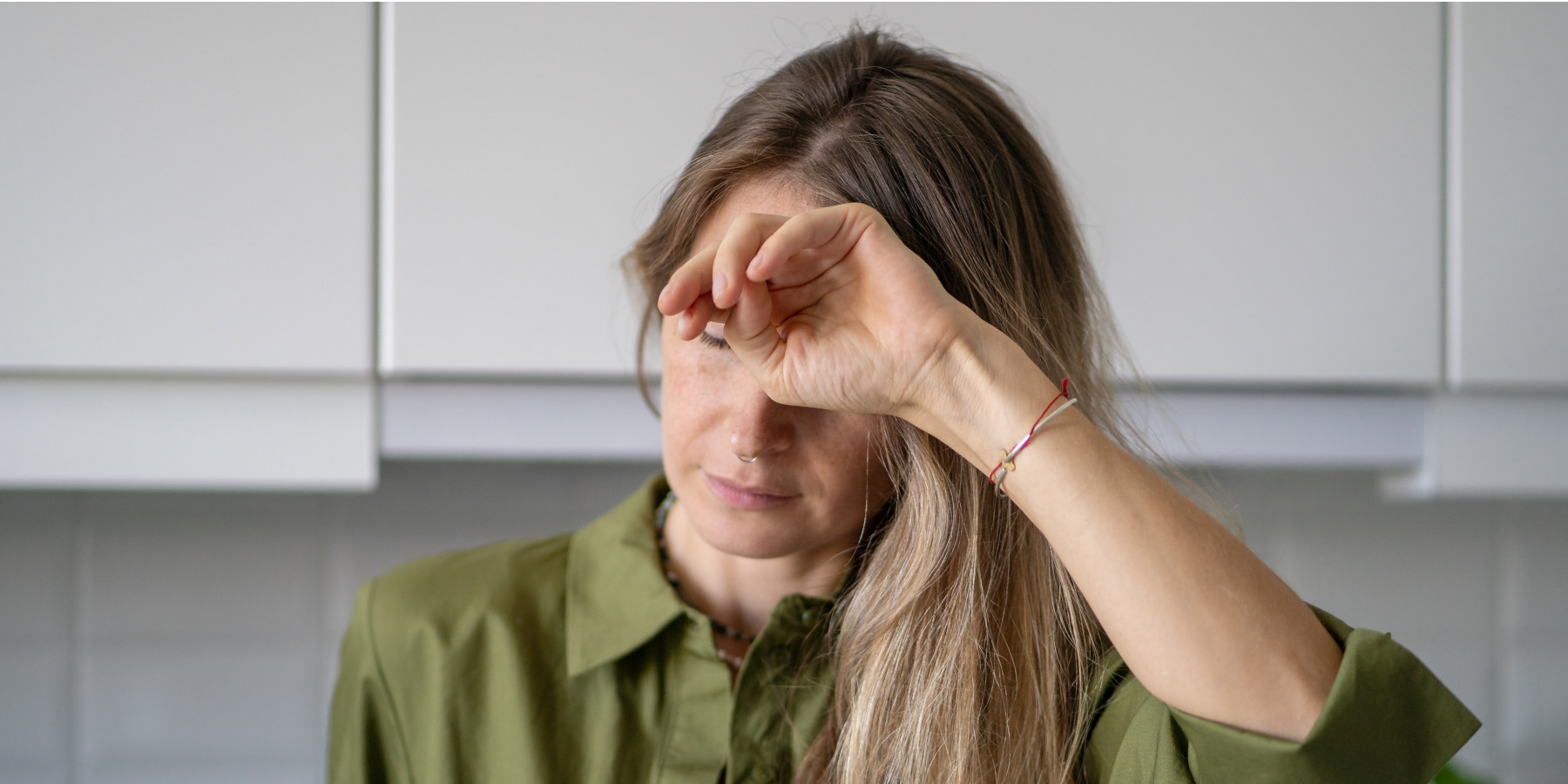 Schwache und müde Frau bedeckt zu Hause ihr Gesicht und ist einer Ohnmacht nahe