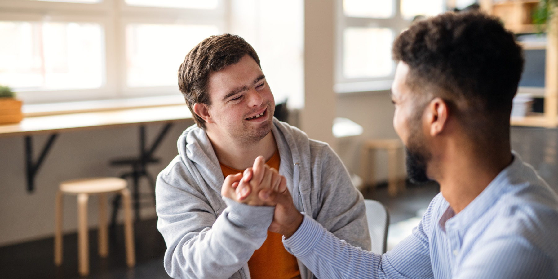 Junger, glücklicher Mann mit Down-Syndrom feiert mit seinem Mentor-Freund in der Schule Erfolge